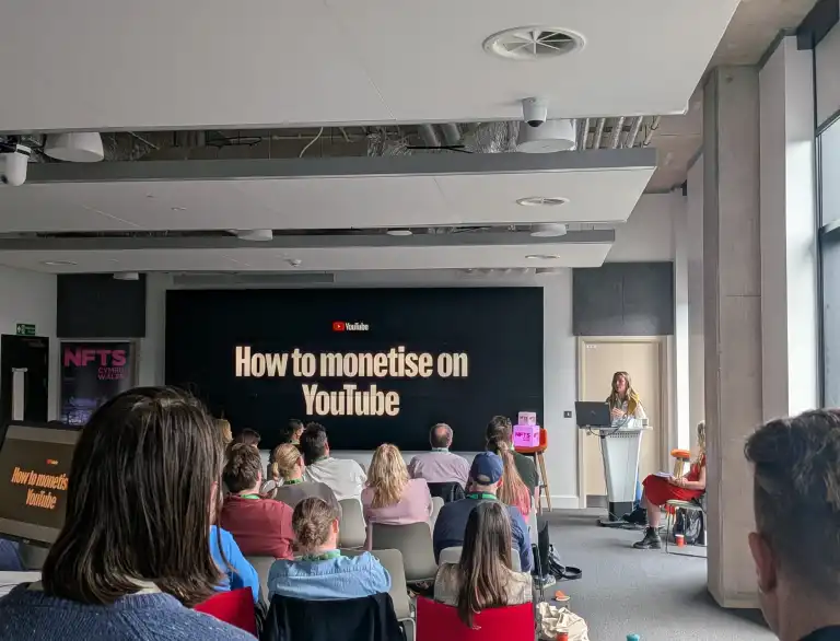 Presentation on monetising YouTube shown to an audience in a modern conference room
