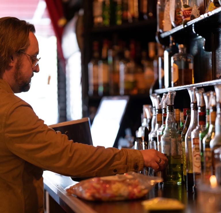 Dan with beard and glasses works behind the bar of porters