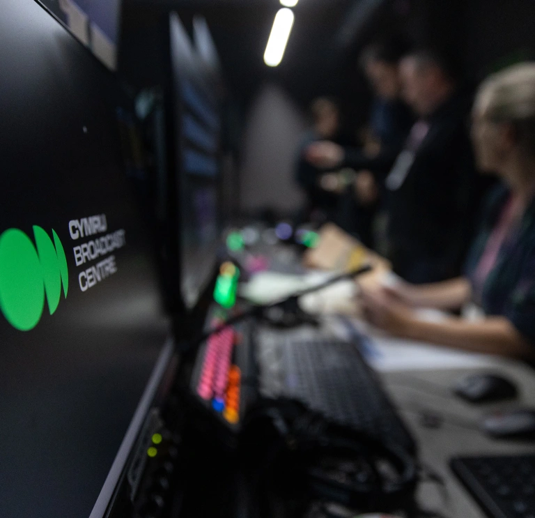 Control room at Cymru Broadcast Centre with staff working at computers and equipment nearby