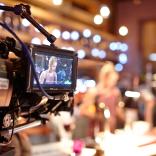 Close up of small camera screen showing image of person on set in background
