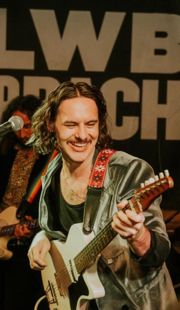 Person on stage with guitar playing live music
